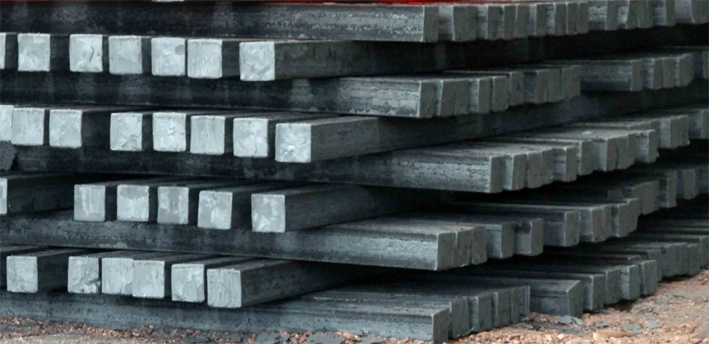 Mild steel billets stacked in bulk inside a factory or warehouse for steel production